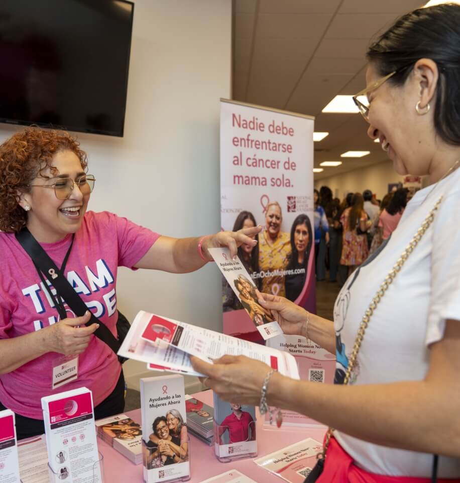 Volunteer sharing Spanish-language breast cancer education materials at a community outreach table
