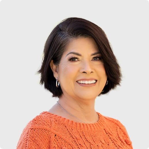 Gabi Barbarena, NBCF board member, smiling and wearing an orange textured sweater.