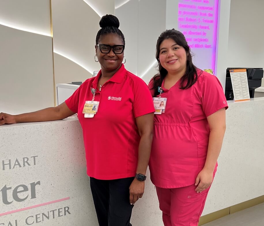 Two healthcare staff members standing together at a medical center reception desk.