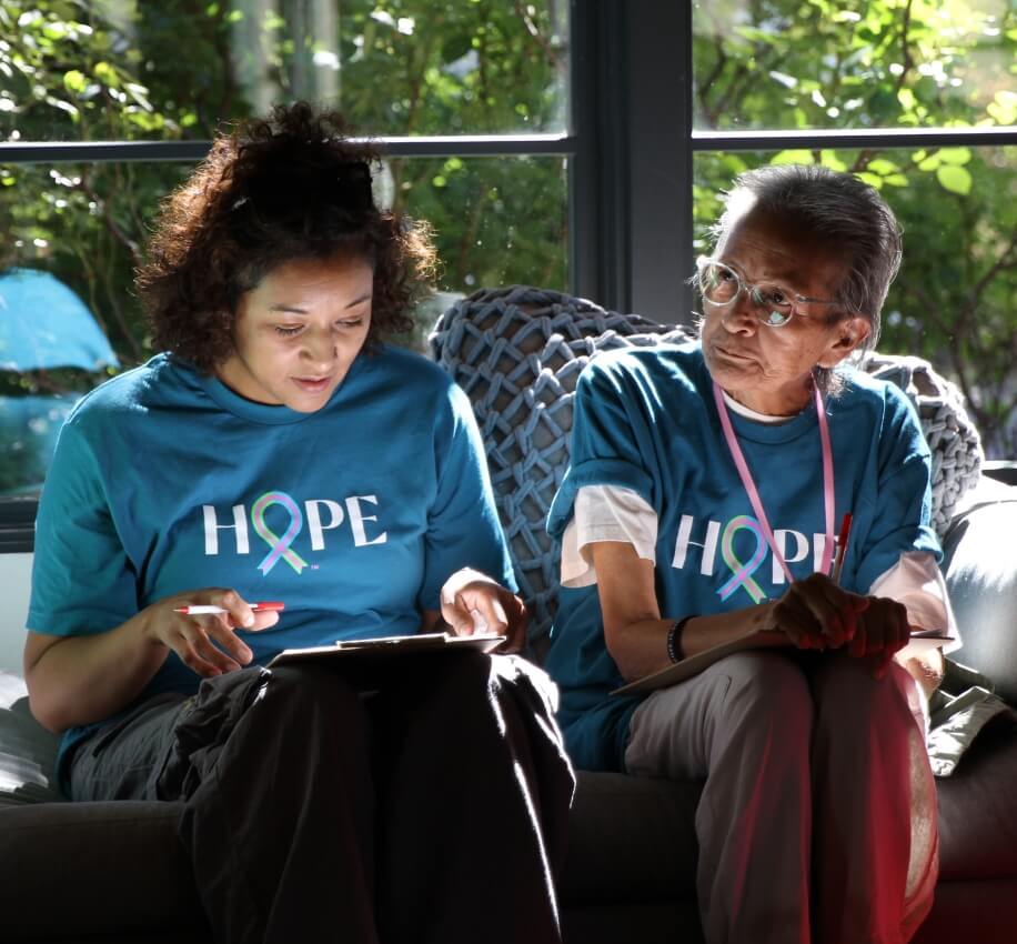 Two women wearing Hope shirts sitting together and reviewing information during a support conversation.